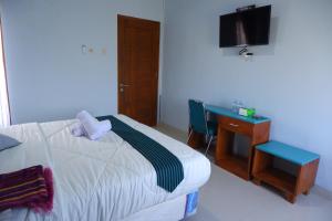 a bedroom with a bed and a desk and a television at Griya Tetirah Syariah Mitra RedDoorz in Bendungan