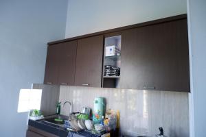 a kitchen with brown cabinets and a sink at Griya Tetirah Syariah Mitra RedDoorz in Bendungan