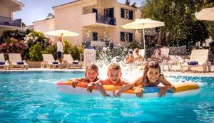 Tres niños están montados en un tubo interior en una piscina en Aminess Port 9 Residence en Korčula