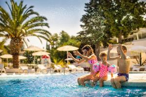- un groupe d'enfants assis dans l'eau à la piscine dans l'établissement Aminess Port 9 Residence, à Korčula