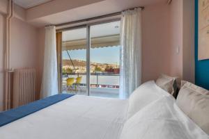 a bedroom with a bed and a large window at Four Seasons Sea View Apartment in Athens
