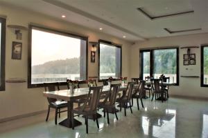 a dining room with tables and chairs and windows at Tavisha Kanatal Hills Chamba in Kanatal