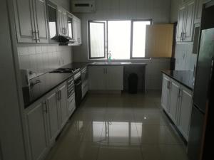 Una cocina con gabinetes blancos y un fregadero y una ventana. en ocean palace self catering lodge, en Durban