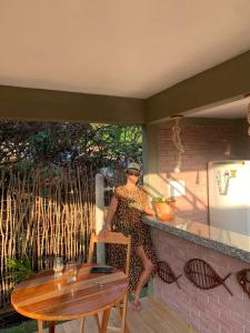 una mujer de pie en un patio con una mesa en Chalé do Rio, en Barreirinhas