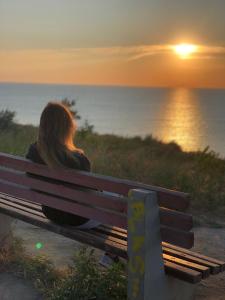 Uma mulher sentada num banco a ver o pôr-do-sol. em Гостевой дом em Sanzhiyka