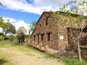 stary kamienny budynek z drewnianym płotem obok niego w obiekcie Casa Rural Finca El Tornero w mieście Aracena