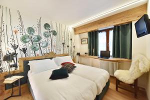 a bedroom with a bed and a chair and a television at Hotel & Ristorante Serenella in Breuil-Cervinia