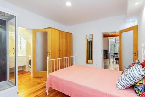 ein Schlafzimmer mit einem rosa Bett in einem Zimmer in der Unterkunft Alfama First Floor in Lissabon
