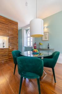 comedor con sillas verdes y mesa de cristal en CLUBE Charming Apartments - Ribeira, en Oporto