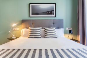 1 dormitorio con 1 cama blanca grande con almohadas a rayas en Apartamentos Líbere Valencia Jardín Botánico, en Valencia