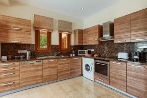cocina con armarios de madera, lavadora y secadora en Aphrodite Hills Rentals - Superior Villas en Kouklia