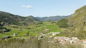 uma vista para um vale com uma aldeia e montanhas em Bel Canto - Chambres d'hôtes Plateau de sault em Roquefeuil