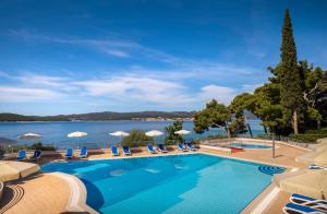 einen Pool mit Stühlen und Sonnenschirmen neben dem Wasser in der Unterkunft Aminess Casa Bellevue in Orebić