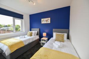 two beds in a bedroom with a blue wall at Greensleeves Place in Troon