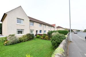 a house with a green yard next to a street at Greensleeves Place in Troon