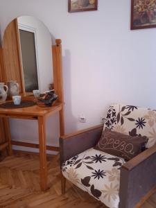 a room with a chair and a table with a mirror at Apartman Breza in Ruma