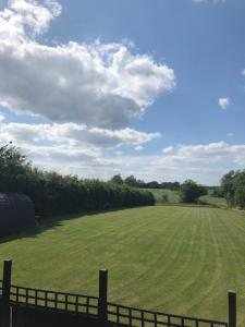 ein großes grünes Feld mit einem Zaun im Vordergrund in der Unterkunft Rockinghams Farm in Layer Marney