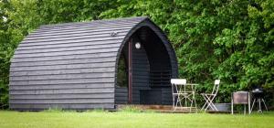 a black shed with chairs and a table in a field at Rockinghams Farm in Layer Marney
