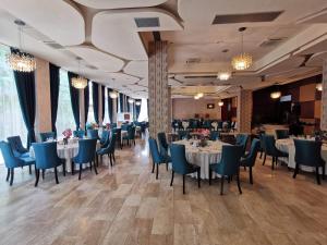 un comedor con mesas blancas y sillas azules en Ramada by Wyndham Hotel Cluj en Cluj-Napoca