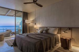 a bedroom with a bed with a view of the ocean at Altera cave villas in Agios Pavlos