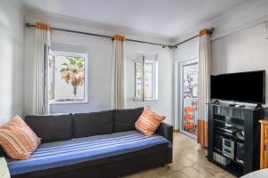 a living room with a couch and a flat screen tv at Regueiró Quarteira Beach Apartment in Quarteira