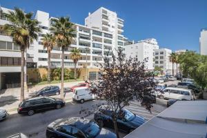 a parking lot with cars and palm trees in a city at Regueiró Quarteira Beach Apartment in Quarteira