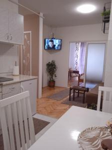 a kitchen and living room with a tv on the wall at Apartman Breza in Ruma