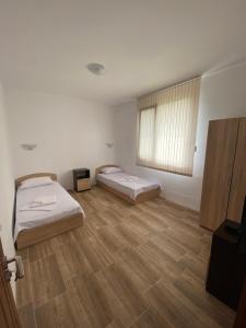 two beds in a room with a wooden floor at Къща за гости Краси in Krapets