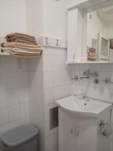 a white bathroom with a sink and a toilet at Apartman Breza in Ruma