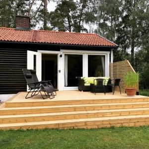 una terraza de madera con sillas y un sofá. en Skogshöjda en Tjörnarp