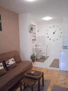 a living room with a couch and a clock on the wall at Apartman Breza in Ruma