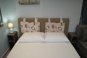 een bed met witte lakens en kussens in een slaapkamer bij Cozy City House in Volos