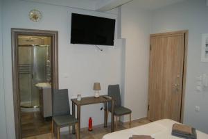 een kamer met een tafel en stoelen en een televisie aan de muur bij Cozy City House in Volos