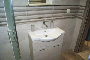 Un baño con lavabo blanco y ducha. en Cozy City House, en Volos