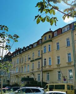 ein großes gelbes Gebäude mit davor geparkt in der Unterkunft Hotel Viktoria Schönbrunn in Wien