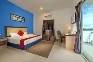 Habitación de hotel con cama, escritorio y ventana en Royal Agate Beach Resort, en Pantai Cenang
