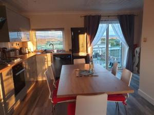a kitchen with a wooden table with chairs and a table and a table at Combe-n-Sea in Haverigg