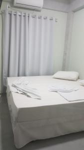 a white bed with white curtains in a room at Hotel Mamma Mia in Aparecida