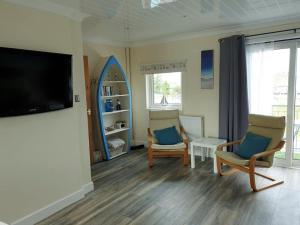 a living room with two chairs and a flat screen tv at Combe-n-Sea in Haverigg