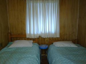 twee bedden in een kleine kamer met een raam bij Cabaña entre Arboles in Villarrica