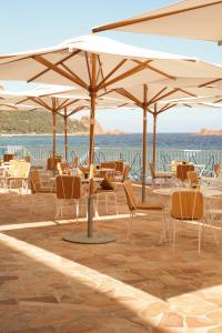 a patio with chairs and tables and umbrellas at Les Roches Rouges, a Beaumier hotel in Saint-Raphaël