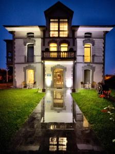 duży biały dom z włączonymi światłami w obiekcie Villa Marta Casa de Indianos Passive House w mieście Villanueva de Ardisana