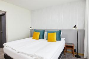 a bedroom with a white bed with yellow and blue pillows at Fosshotel Stykkisholmur in Stykkishólmur