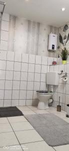 a white tiled bathroom with a toilet and a sink at Monteurwohnung Krüger Bitterfeld-Wolfen in Steinfurth