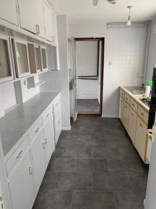 cocina con armarios blancos y suelo de baldosa en 5 Bedroom House with outdoor space, en Upminster