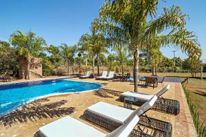a pool with lounge chairs and a palm tree at Pousada Pé na Terra in Brotas