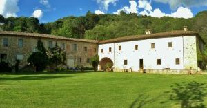 un grand bâtiment blanc avec une pelouse dans l'établissement Agriturismo "Ai frati", à Pieve Fosciana