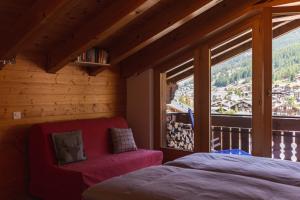 a bedroom with a bed and a large window at Dachwohnung Balma-great overview of Zermatt in Zermatt