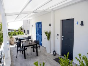d'une terrasse avec des tables et des chaises et une porte bleue. dans l'établissement Le Casette sul Mare B&B, à Cittadella del Capo