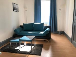 a living room with a blue couch and a table at STAY IN MULHOUSE in Mulhouse